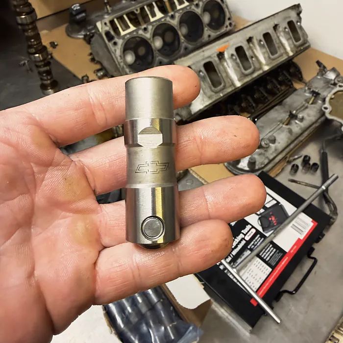 A hydraulic lifter, with the cylinder heads on the bench behind